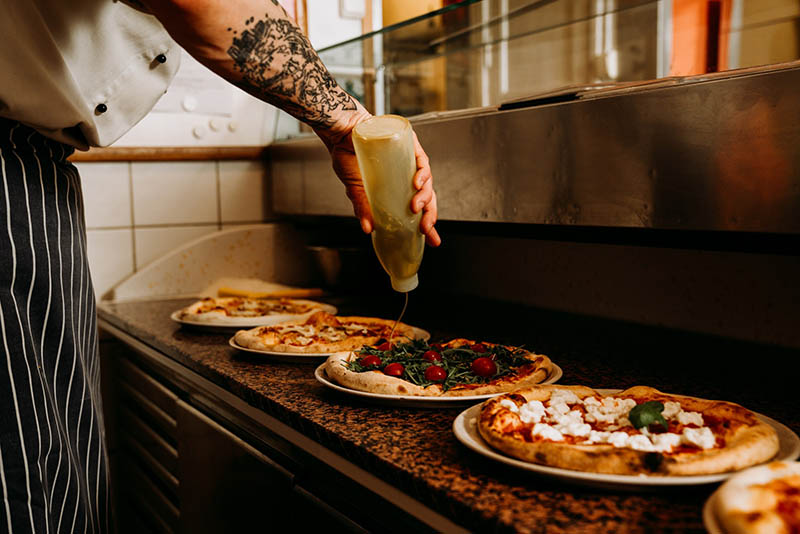 Chef giving the final touches to a pizza