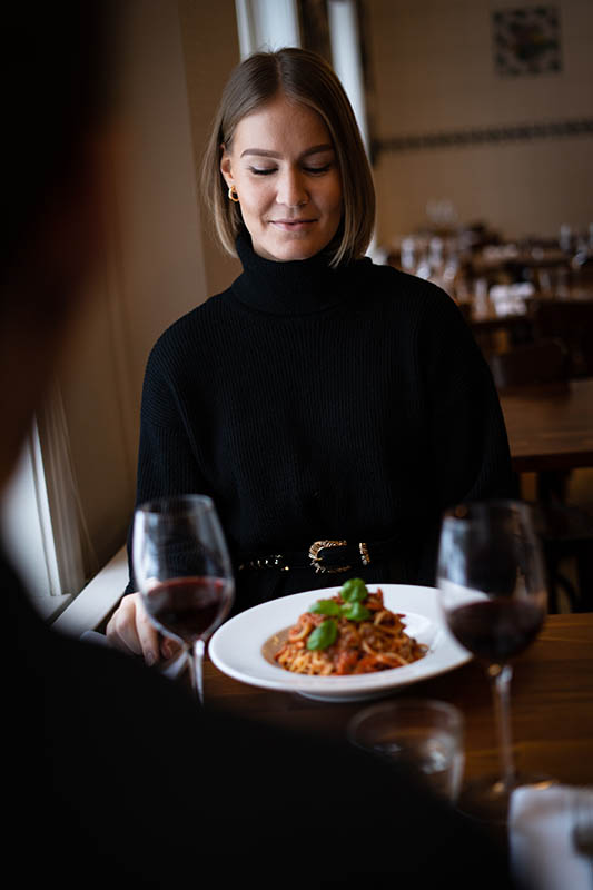 A plate fo pasta and two glasses of red wine