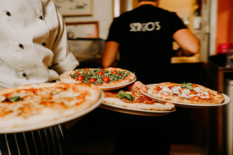 waiter serving pizzas in ravintola sergio